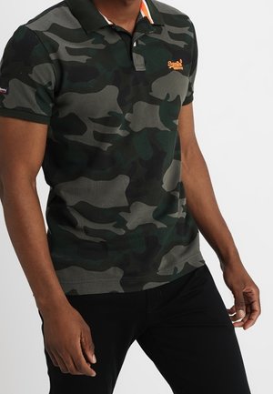 Polo-shirt i mørkegrønt camouflage-mønster, med klassisk krave, korte ærmer og en orange logo på brystet.