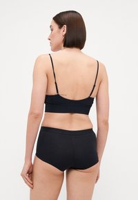 Black bra and matching brief set, made from soft fabric. The bra features adjustable straps and a seamless design for comfort.