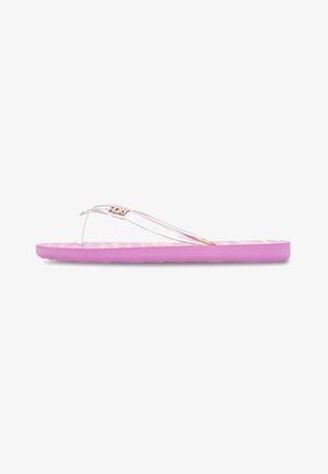 Chausson violet avec une semelle texturée, des brides transparentes et un petit logo métallique. Semelle plate avec une base rembourrée.