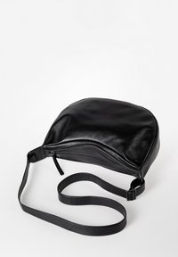 Borsa in pelle nera con forma arrotondata, chiusura con zip e lunga tracolla regolabile. Texture liscia e design minimalista.