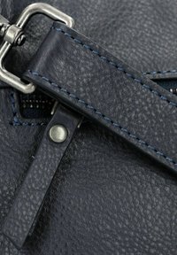 Cinghia in pelle di un intenso blu navy, con cuciture blu a contrasto e accessori in metallo. Superficie testurizzata con una finitura liscia.