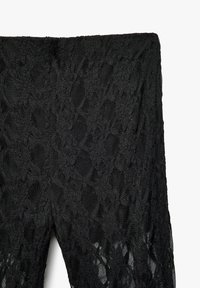 Zwarte kant legging met een delicate bloemenprint, semi-doorzichtige textuur en een elastische tailleband voor een strak silhouet.