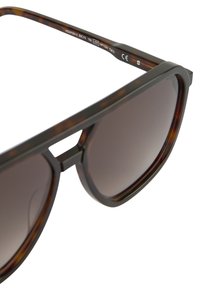  Schildpadbril met donkere vervaagde lenzen, rechthoekige vorm, dikke monturen en een uitsparing tussen de lenzen voor een moderne uitstraling.