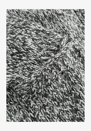 Textile tricoté en noir et blanc avec une texture épaisse et bulky. Le fil présente un mélange de fibres torsadées créant une surface à motifs.