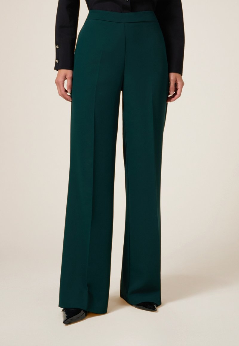 Pantalones de pierna ancha en tejido verde oscuro, con una cinturilla alta y líneas limpias. Textura suave sin patrones o acentos visibles.