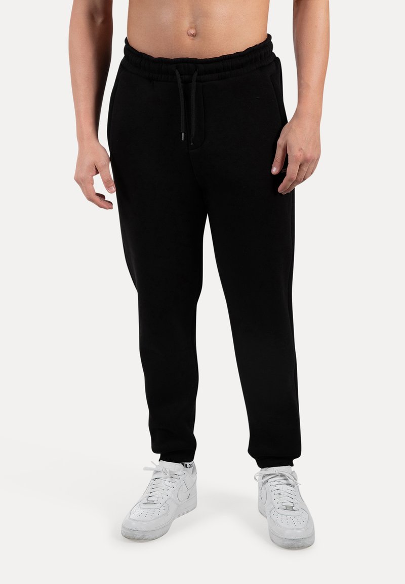 Svarte bomulds joggers med elastisk talje og snor, med en afslappet pasform og tapered ben. Pairing med hvide sneakers.