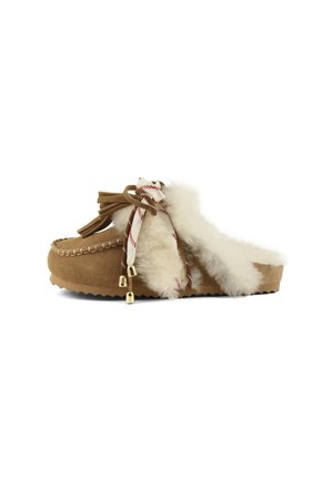 Chaussure slip-on en daim marron avec doublure en fourrure blanche douce, détails cousus et lacets décoratifs avec pompons et embouts métalliques dorés.