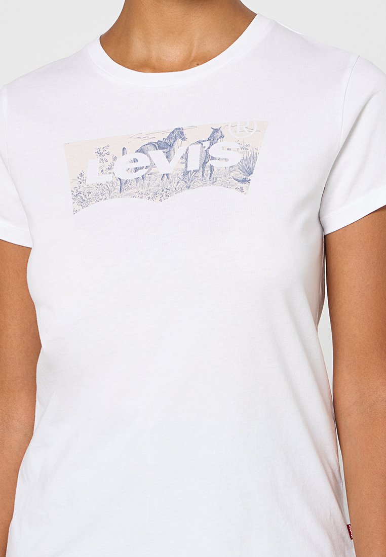 Camiseta de algodón blanca con un gráfico en azul y crema que incluye el texto "Levi's" y ilustraciones inspiradas en la naturaleza en la parte frontal. Mangas cortas.