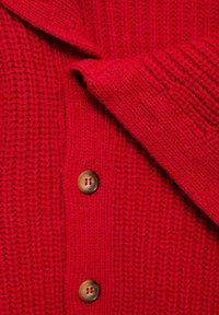Cardigan en tricot rouge avec une texture côtelée, grand col et trois boutons marron sur le devant. Matériau doux et chaud.