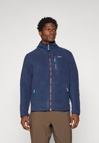 Navy fleece jacket with a high collar, zip closure, and contrasting blue zipper pulls. Features two side pockets and a logo on the chest.