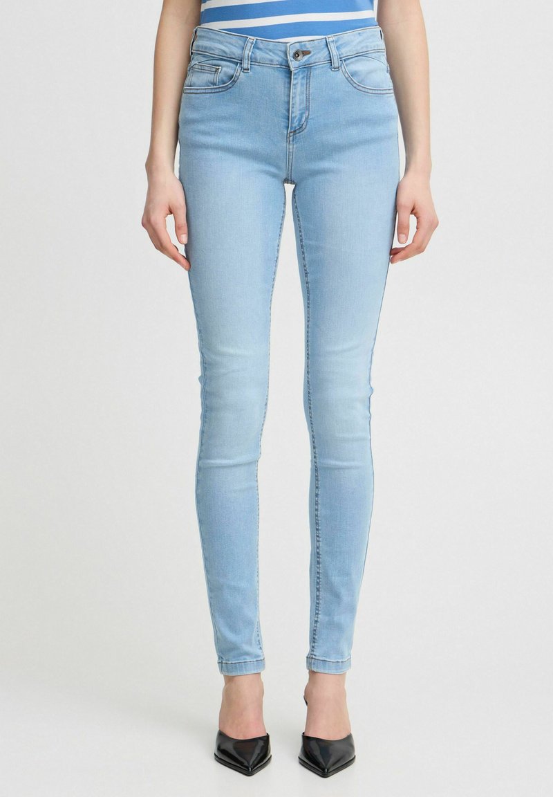 Jeans ajustados de color azul claro, hechos de denim. Presentan un diseño de cinco bolsillos, pasadores para cinturón y un cierre de cremallera con botón.