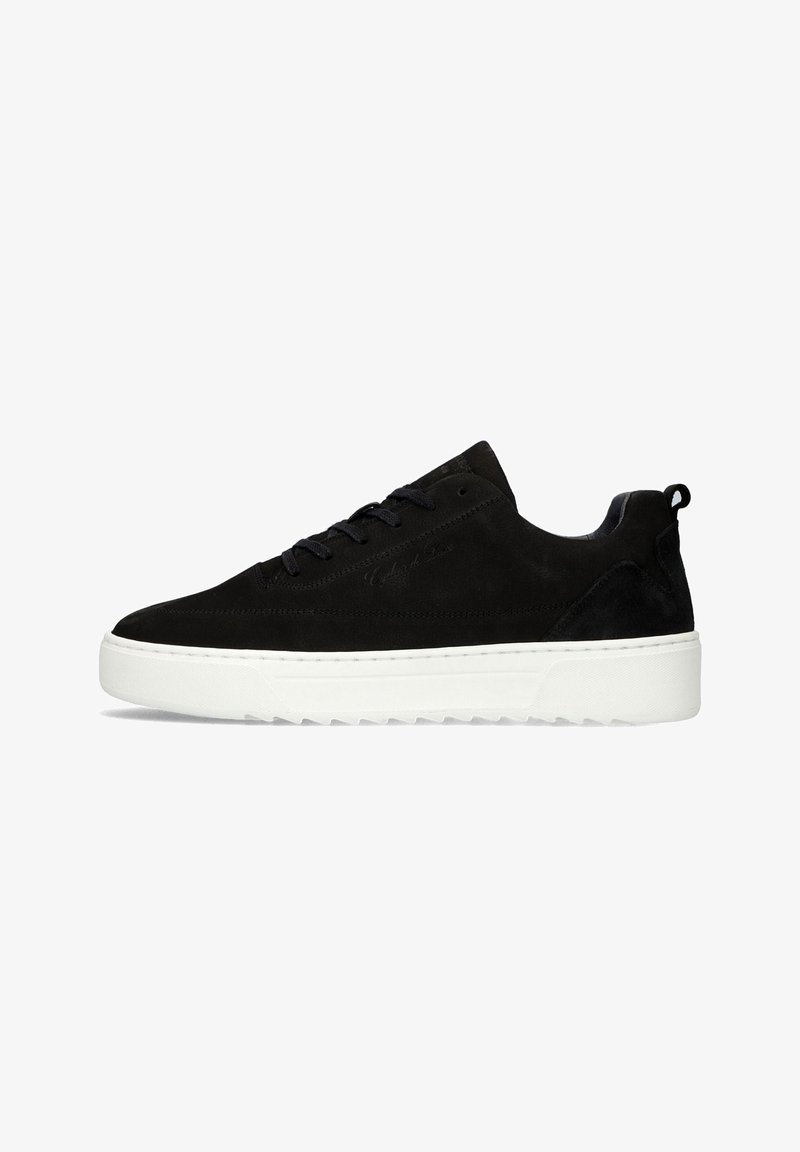 Zwarte lage suède sneaker met zwarte veters en een dikke witte rubberen zool op een witte achtergrond.