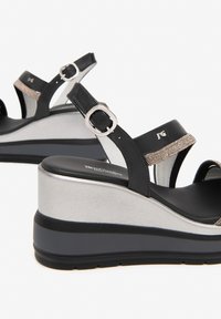 Black wedge sandals with silver accents, textured straps, buckle detail, and a platform sole, featuring a smooth and glossy finish.