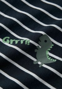 Gestreifter Stoff in Marineblau und Weiß mit einem grünen Dinosauriergrafik und dem Text "Grrr!!" in Hellgrün, der verspielte Designdetails hervorhebt.