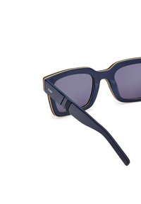 Laivaston aurinkolasit neliönmuotoisella kehykellä, kultaisilla yksityiskohdilla reunoilla, tummilla linsseillä ja tyylikkäällä, modernilla muovisuunnittelulla.