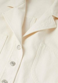Krémová denimová košile s límečkem, kovovými snap knoflíky a náprsní kapsou s texturovanou látkou.