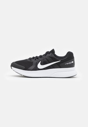 Baskets de sport noires avec tige en mesh, logo Nike blanc, design à lacets, semelle blanche rembourrée et semelle extérieure noire texturée.