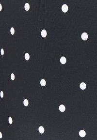 Schwarzer Stoff mit gleichmäßig verteilten weißen Pünktchen, der eine glatte Textur und ein einfaches Musterdesign zeigt.