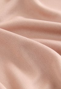 Hellrosa strukturiertes Gewebe mit subtilen Falten und weichen Schatten, die das Strickmuster und die glatte Oberfläche hervorheben.