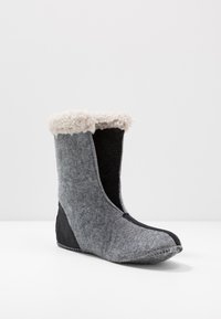 Bota de mezcla de lana en gris con un ribete negro y un puño beige esponjoso. Presenta una punta redondeada y detalles de costura a lo largo de la suela.