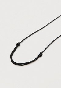 Μαύρο κορδόνι για κολιέ με απλό σχέδιο και δύο κόμπους για ρύθμιση μήκους· κατασκευασμένο από υφαντό υλικό με ομαλή υφή.