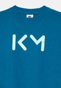 Turkusowa bluza Nike z ribbowanym okrągłym dekoltem i dużym białym logo z teksturowymi paskami na środku.