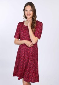 Rotes Blumenkleid mit kurzen Ärmeln und quadratischem Ausschnitt. Aus leichtem Stoff gefertigt, hat es einen ausgestellten Saum und kleine Blumenmuster.