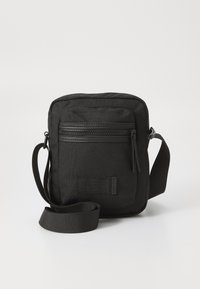 Borsa a tracolla nera realizzata in tessuto testurizzato, con una tasca anteriore con zip e una tracolla regolabile. Presenta un piccolo patch con il logo sulla parte anteriore.