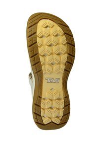 Teva sandal sål, der har et struktureret honningkombmønster i tan gummi med et hvidt logo. Holdbart, fleksibelt design til godt greb.