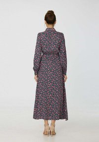 Robe longue bleu marine à motif floral rose, taille ceinturée, col à revers et manches longues. Tissu lisse avec une silhouette longue jusqu'aux pieds.