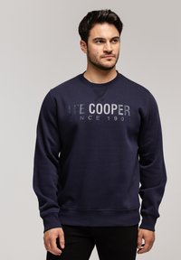 Granatowy sweatshirt z okrągłym dekoltem, z napisem "LEE COOPER SINCE 1903" w kontrastowym nadruku na klatce piersiowej. Miękka tekstura materiału.