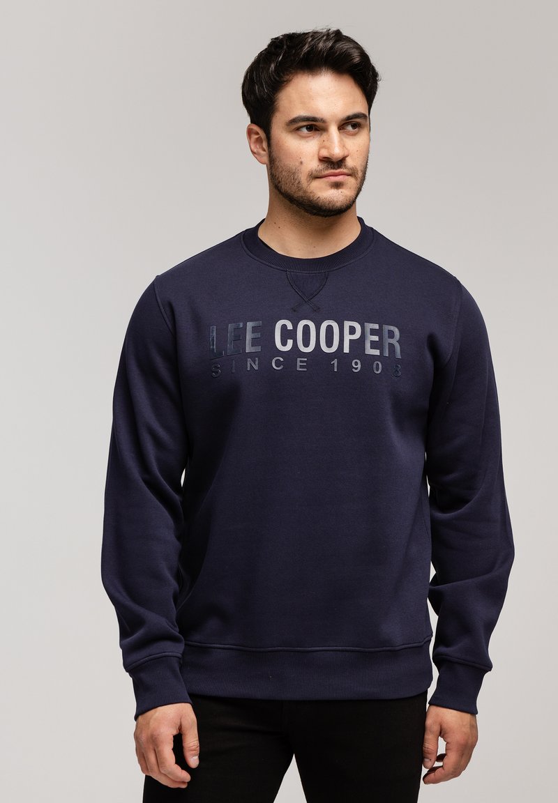 Granatowy sweatshirt z okrągłym dekoltem, z napisem "LEE COOPER SINCE 1903" w kontrastowym nadruku na klatce piersiowej. Miękka tekstura materiału.