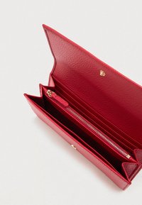 Rode leren portemonnee met textuur, opengeklapt om het ritsvakje voor munten, meerdere kaartsleuven en een gouden drukknoopsluiting aan de binnenkant te tonen.