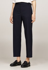Pantaloni tailored blu navy con frontale piatto, vestibilità slim e gamba dritta. Realizzati in tessuto liscio con una sottile texture.