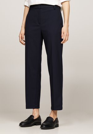 Pantaloni tailored blu navy con frontale piatto, vestibilità slim e gamba dritta. Realizzati in tessuto liscio con una sottile texture.