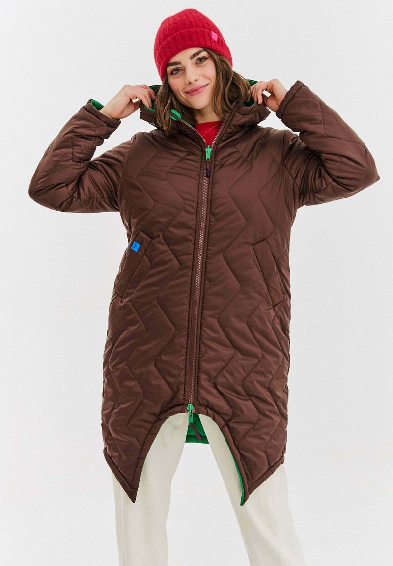 Hnedý prešívaný dlhý kabát so zelenými akcentmi a vysokým golierom. Obsahuje zipové zapínanie a dve bočné vrecká. Tkanina vyzerá hladko a nadýchnuto.