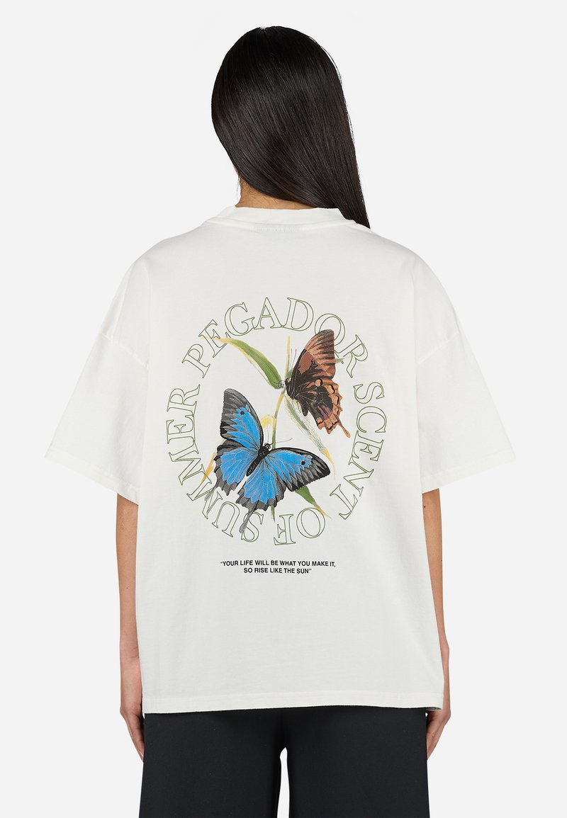 Camiseta de algodón blanca con un gran gráfico de mariposa en azul y marrón en la parte posterior, con texto verde que dice "PEGADOR AROMA DE VERANO."