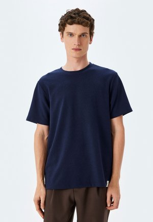 Navy blue kortærmet t-shirt, rund halsudskæring, lavet af blødt stof, med en lige pasform og et lille logo mærke ved nederkanten.
