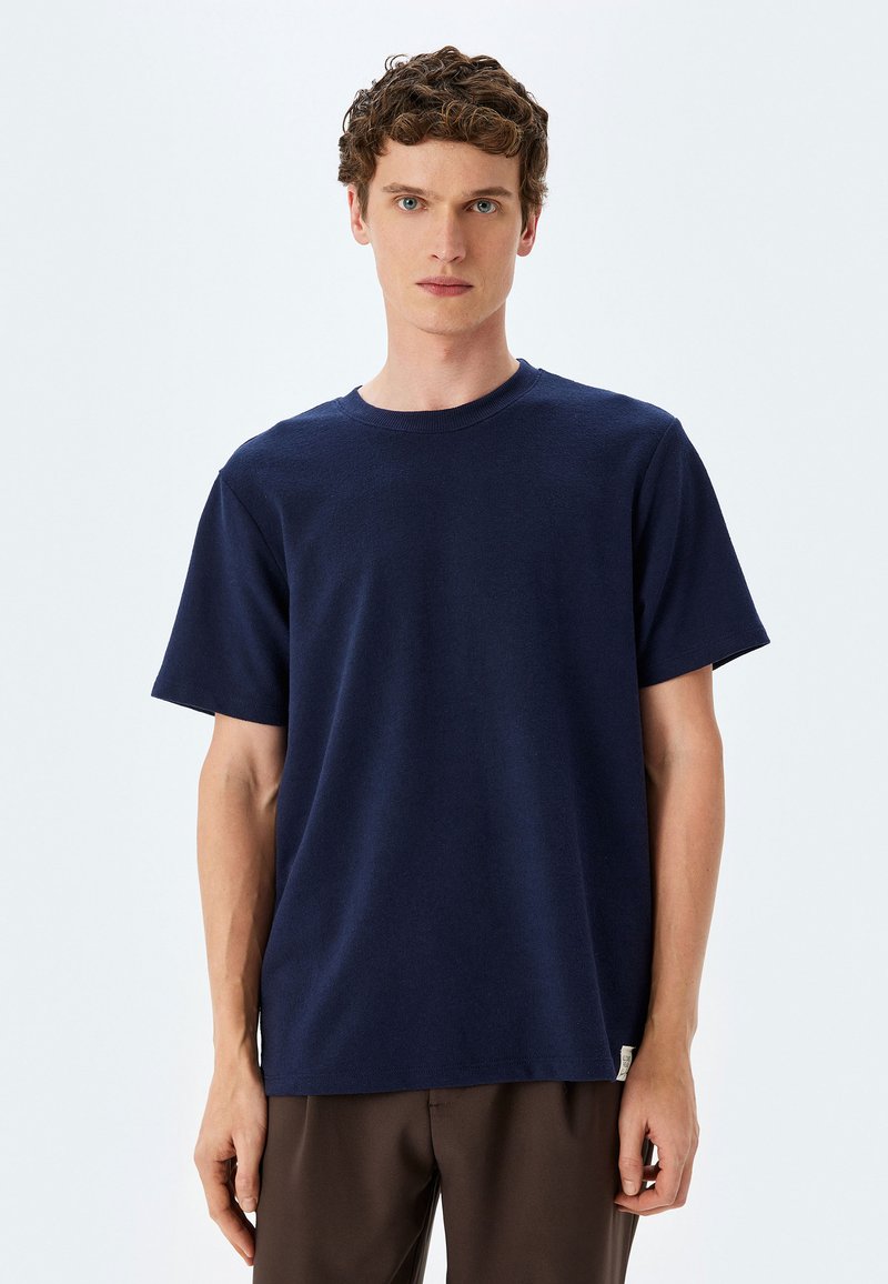 Navy blue kortærmet t-shirt, rund halsudskæring, lavet af blødt stof, med en lige pasform og et lille logo mærke ved nederkanten.