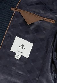 Navy blue slim fit jacket interior with a textured pattern and brown accents. Features a label displaying brand and size information.