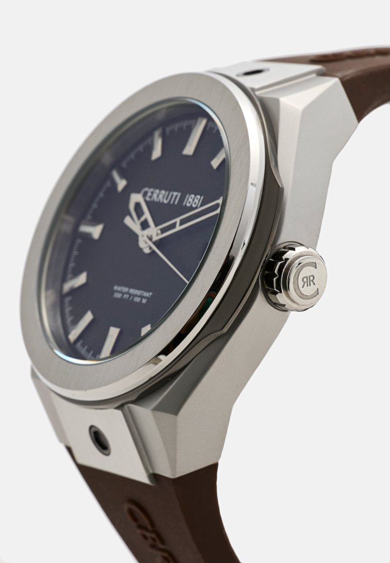 Montre Cerruti 1881 avec un boîtier en acier inoxydable, un cadran bleu foncé, des index heures en argent, un bracelet en caoutchouc marron et un détail texturé sur la couronne.