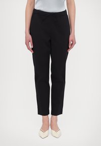 Black, tapered trousers with an elastic waistband and drawstring. Smooth fabric with a slim fit, ending just above the ankle.