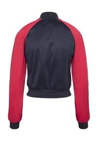 Sportjacket met een marineblauw lichaam, rode mouwen, ribgebreide manchetten en een korte kraag, gemaakt van gladde, lichte stof.