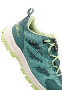 Teal fottur for hiking med en teksturert overdel, mesh-detaljer og limegrønn såle. Funksjoner inkluderer en merket trekkflik og lisser.