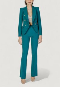Completo giacca e pantaloni a palazzo color teal. Presenta bottoni dorati, design strutturato e un reggiseno in pizzo testurizzato sotto.