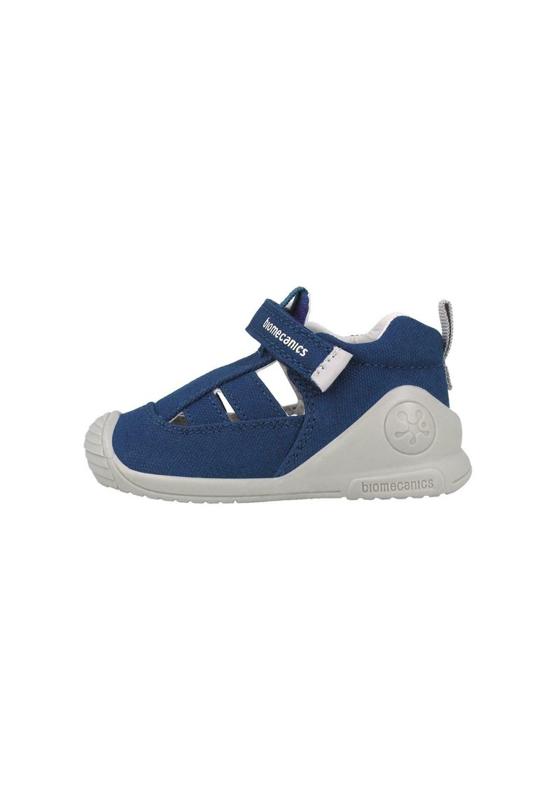 Blauer Schuh aus Stoff mit geschlossenem Zehenbereich, weißer Gummisohle, verstellbarem Riemen und Cut-Out-Details an den Seiten für Atmungsaktivität.