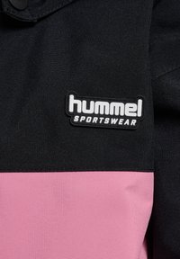 Zwarte en roze sportjack met een textuurstof, voorzien van een opvallend "hummel SPORTSWEAR" logo op een zwart label.
