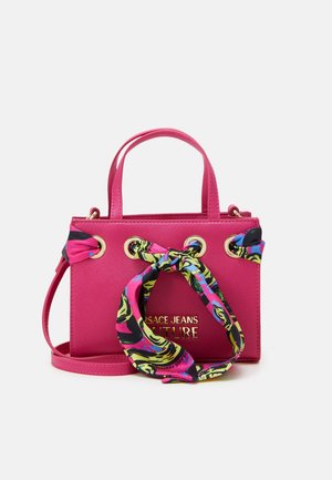 Lille knaldrød håndtaske med gulddetaljer, et farverigt mønstret tørklæde bundet igennem dem og et gyldent "Versace Jeans Couture"-logo.