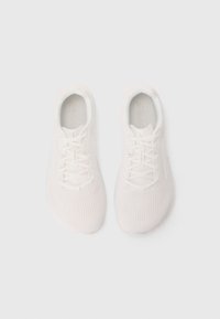 Baskets blanches avec une tige texturée, des lacets et un design à bout rond. Matériaux légers et flexibles.