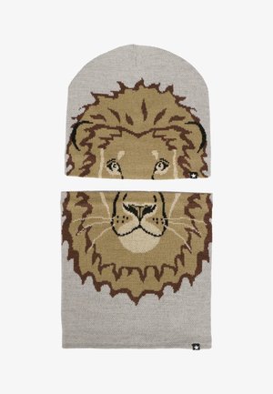 Ensemble bonnet et écharpe tricotés présentant un design de lion en marron et beige sur un fond gris clair. Texture douce avec un accent logo.